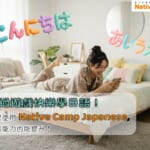 一位年輕女性穿著舒適的睡衣，躺在床上，正在用手機玩遊戲，臉上帶著笑容。背景是她的溫馨臥室，牆上有色彩鮮艷的氣球組成的日語問候語『こんにちは』和『あいうえお』，顯示出輕鬆愉快的氛圍。畫面下方的文字寫著『透過遊戲快樂學日語！如果使用Native Camp Japanese，會話能力也能提升！』