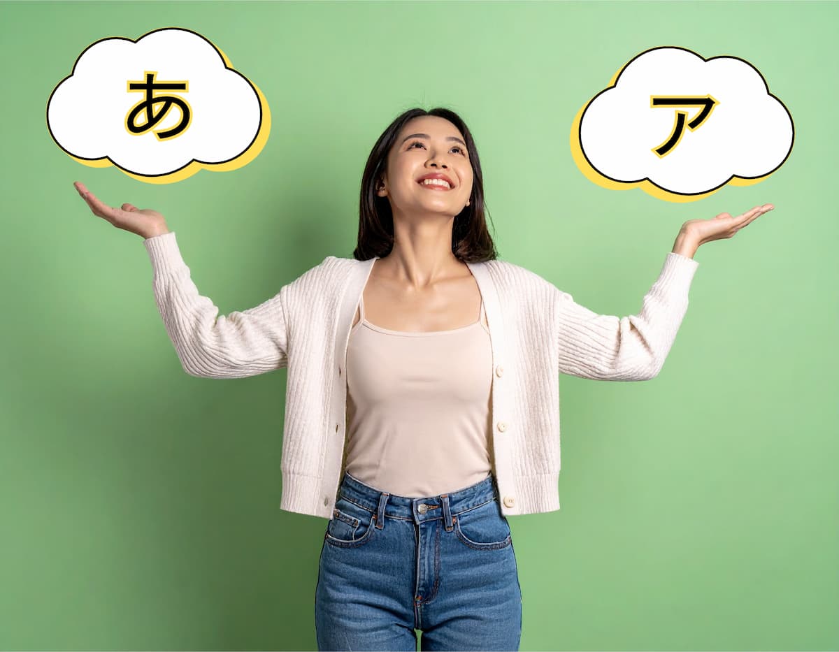 一位年輕女性站立在綠色背景前，雙手各舉著一個包含日文字「ひらがな」和「カタカナ」的雲形圖案。她微笑著，表情輕鬆愉快，顯示出學習日文的開心與積極態度。